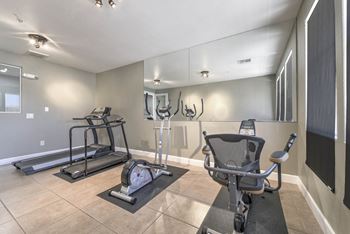 A gym with a treadmill, elliptical trainer and a stationary bike.